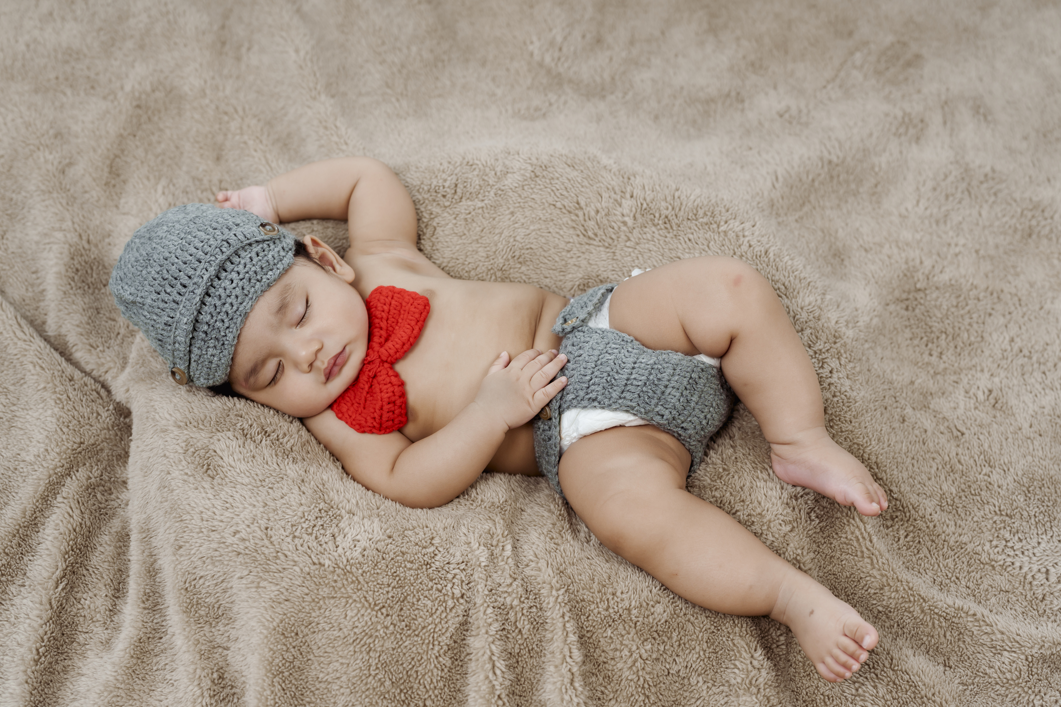 3-month-old Asian newborn in a knitted sweater is happily sleeping warmly on the rug in the bedroom. Concept Happy Family