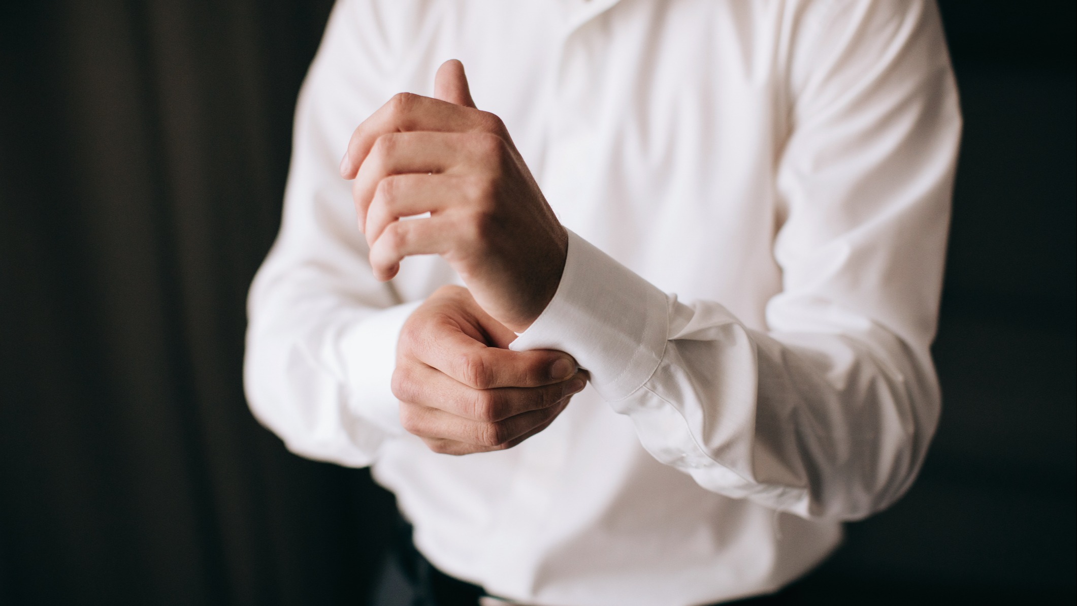 A man putting on a button-up shirt