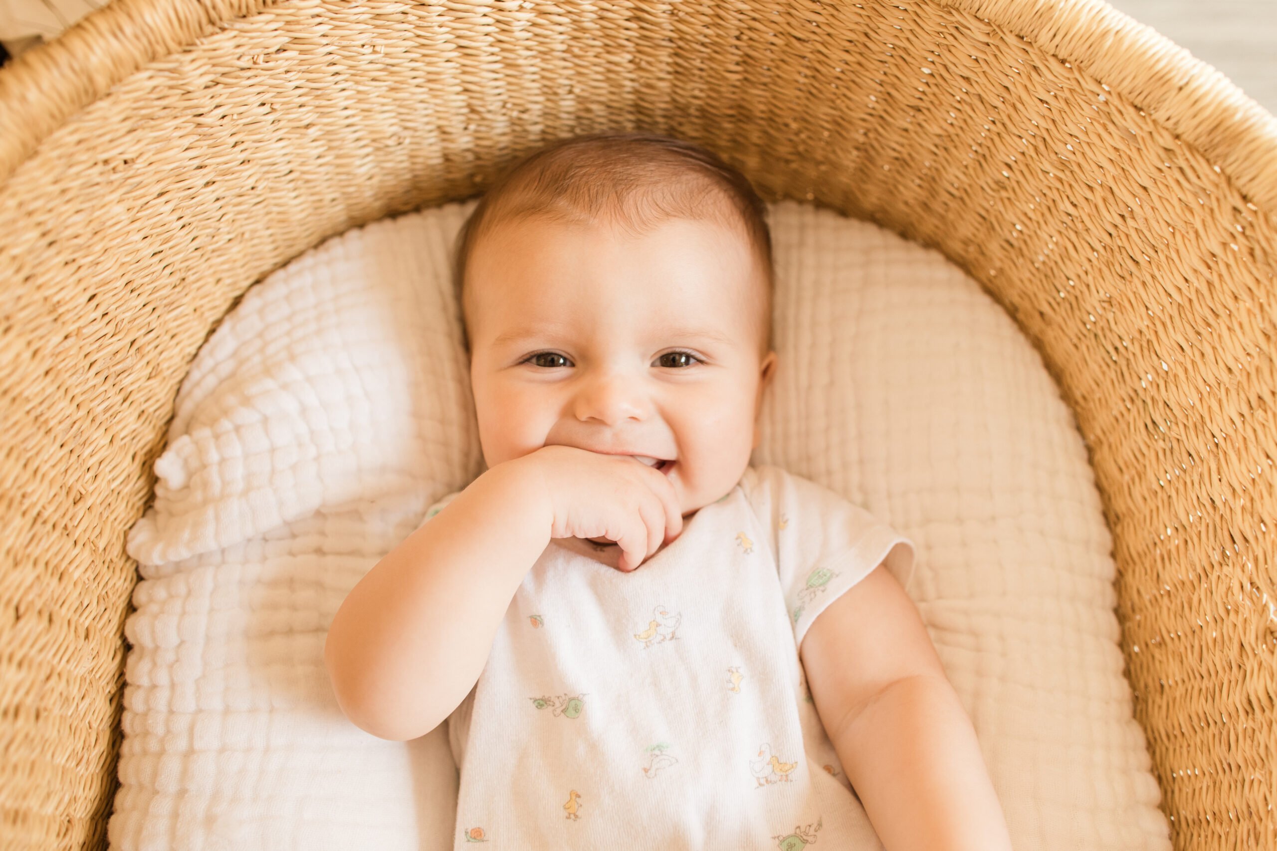 A 29-Week-Old Baby Boy in a Cozy Cotton Blanket in a Seagrass Moses Basket in a Neutral Modern Home