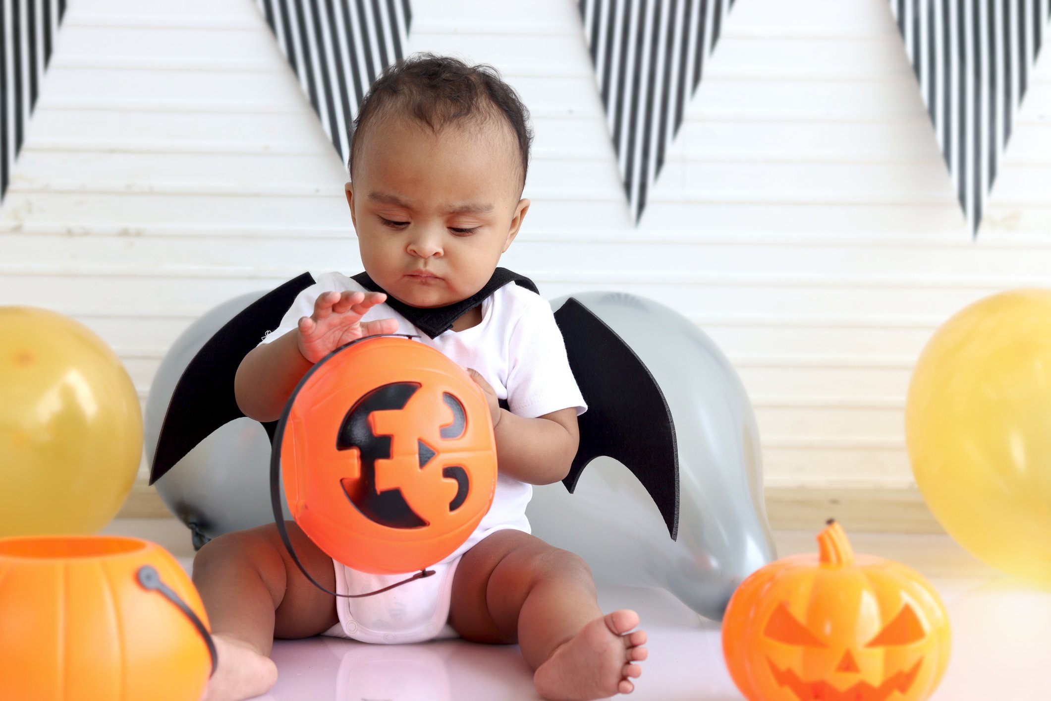 Adorable African baby kid dressing up in vampire fancy Halloween costume with black bat wings, cheerful little cute child go to party, playing trick or treat, Happy Halloween celebration.