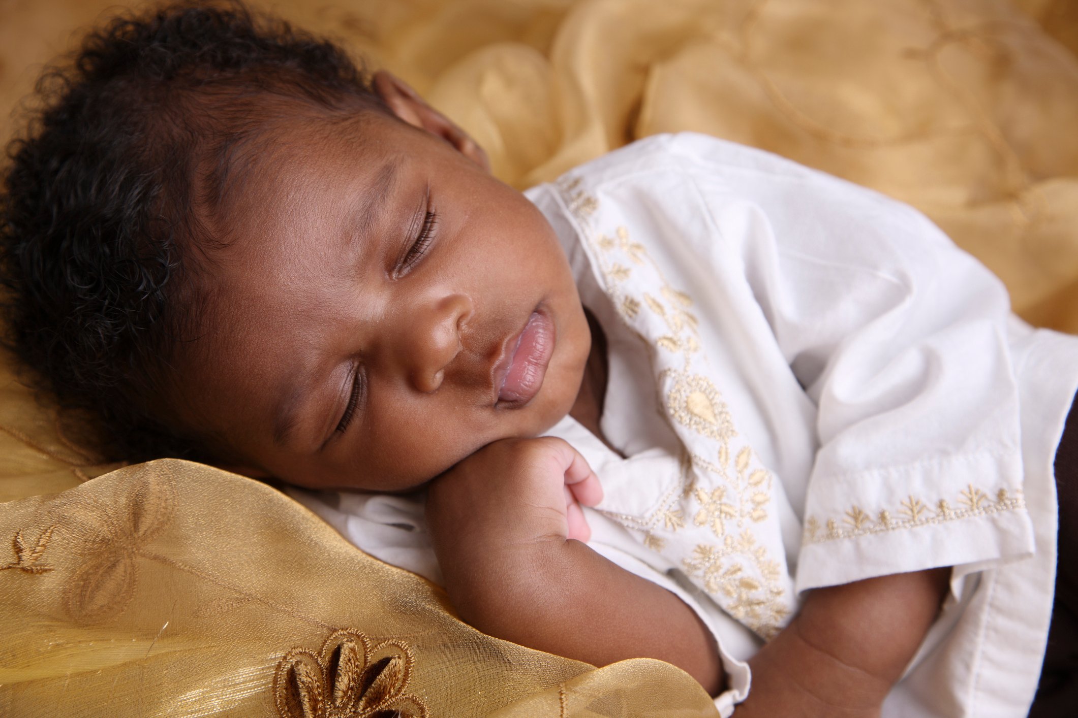 African-American baby with curly hair sleeping on a blanket