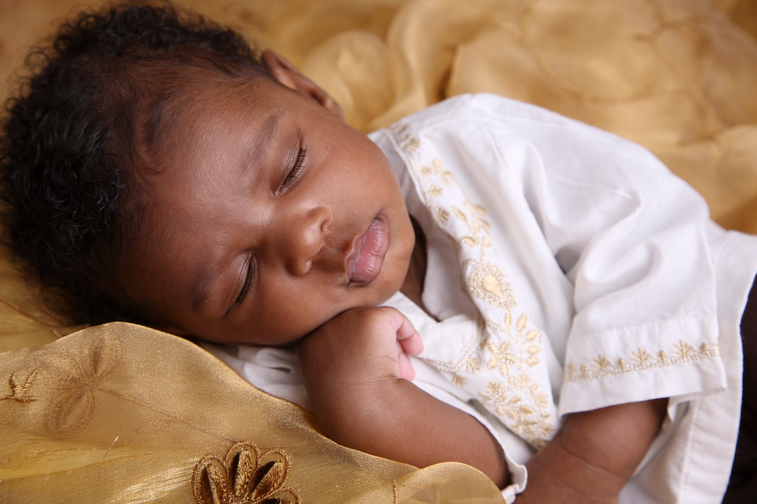 African-American baby with curly hair sleeping on a blanket
