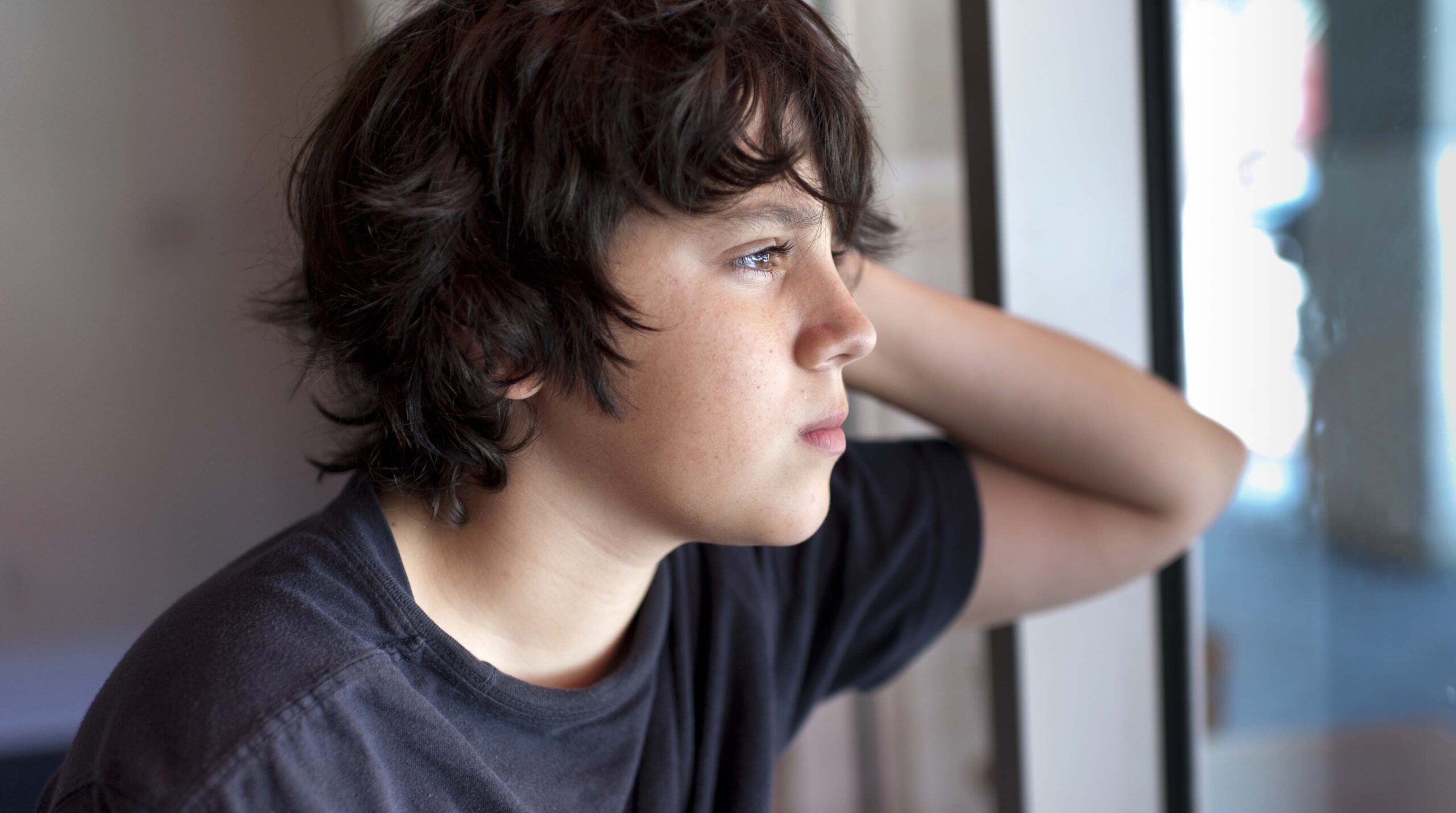 Pensive child looking through a window