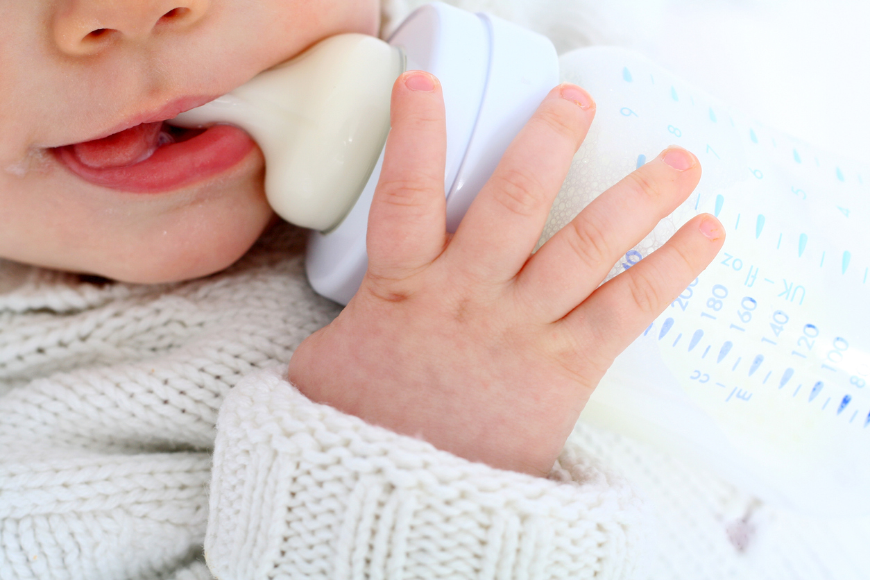 Baby is drinking milk out of a bottle
