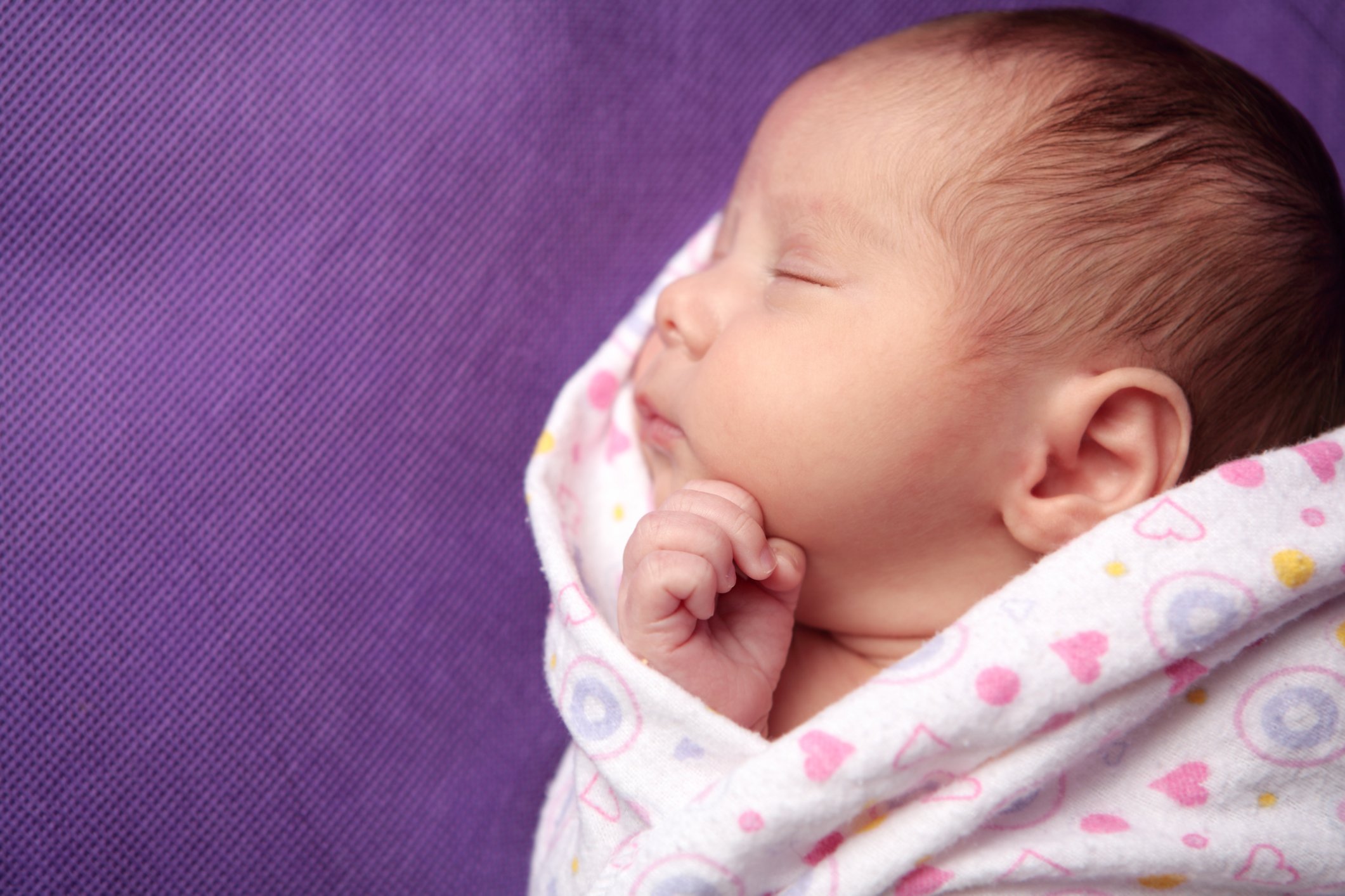 A newborn girl sleeping while being swaddled