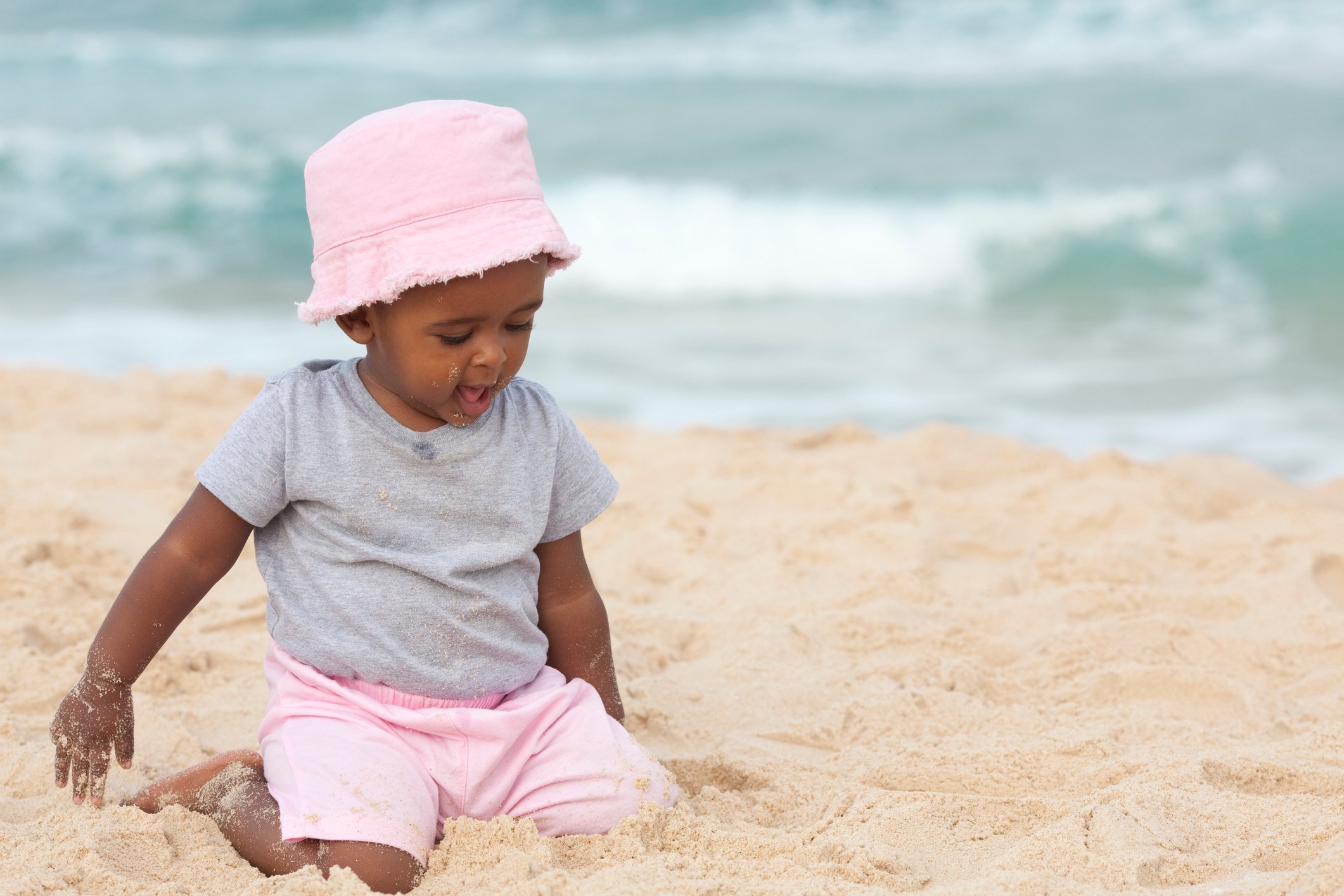 Kid playing with sand on the beach.