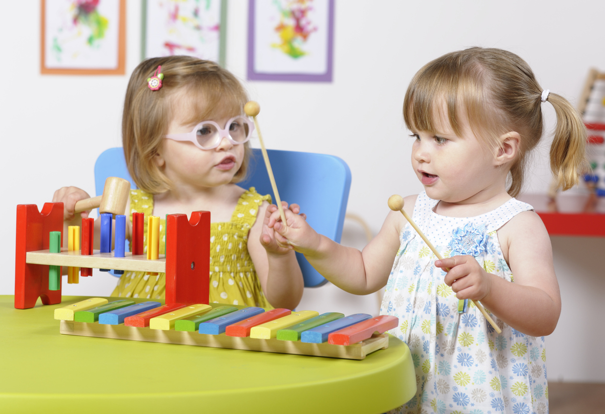 Toddler Girls Interacting  And Enjoying Music In A Nursery Setting