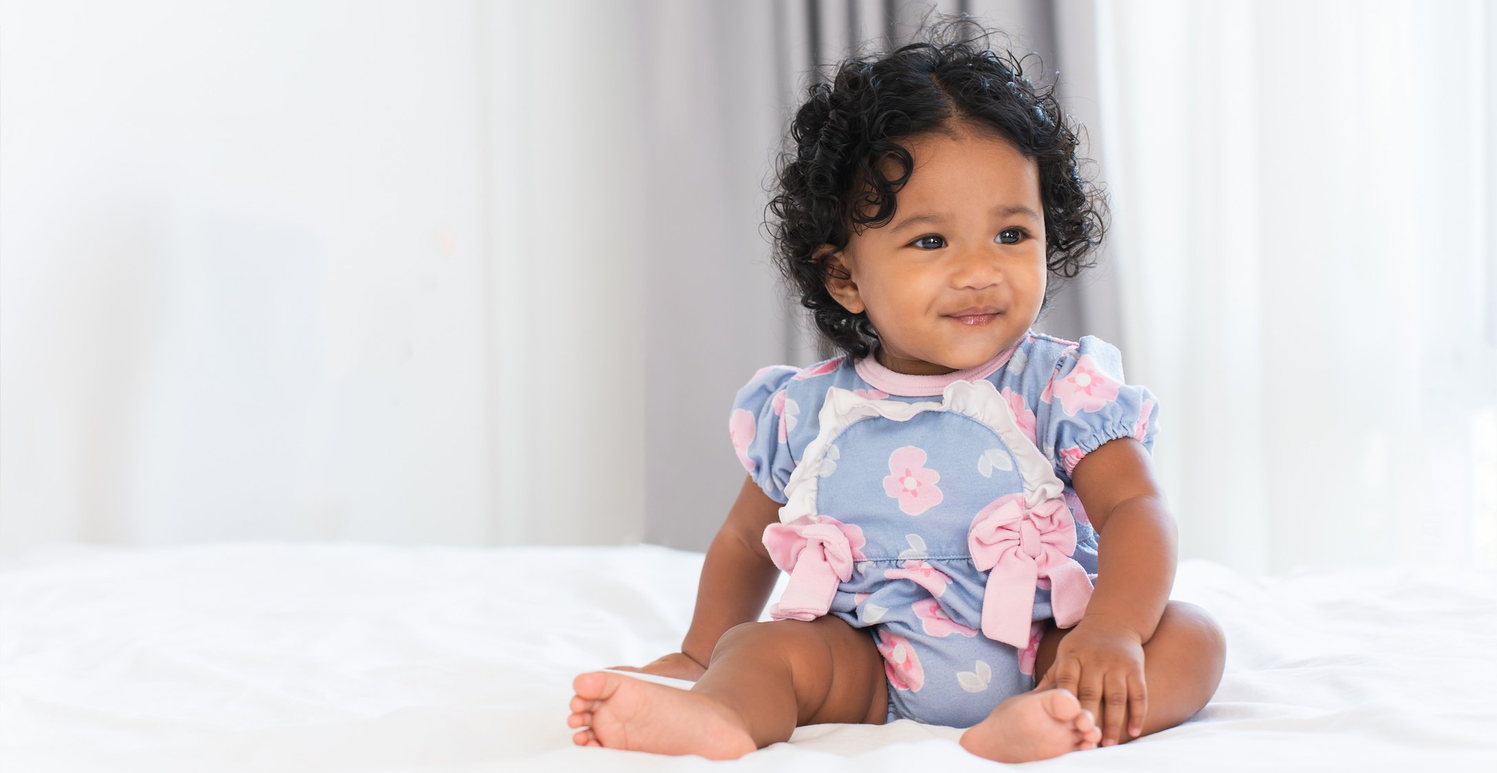 Baby girl sitting on a bed