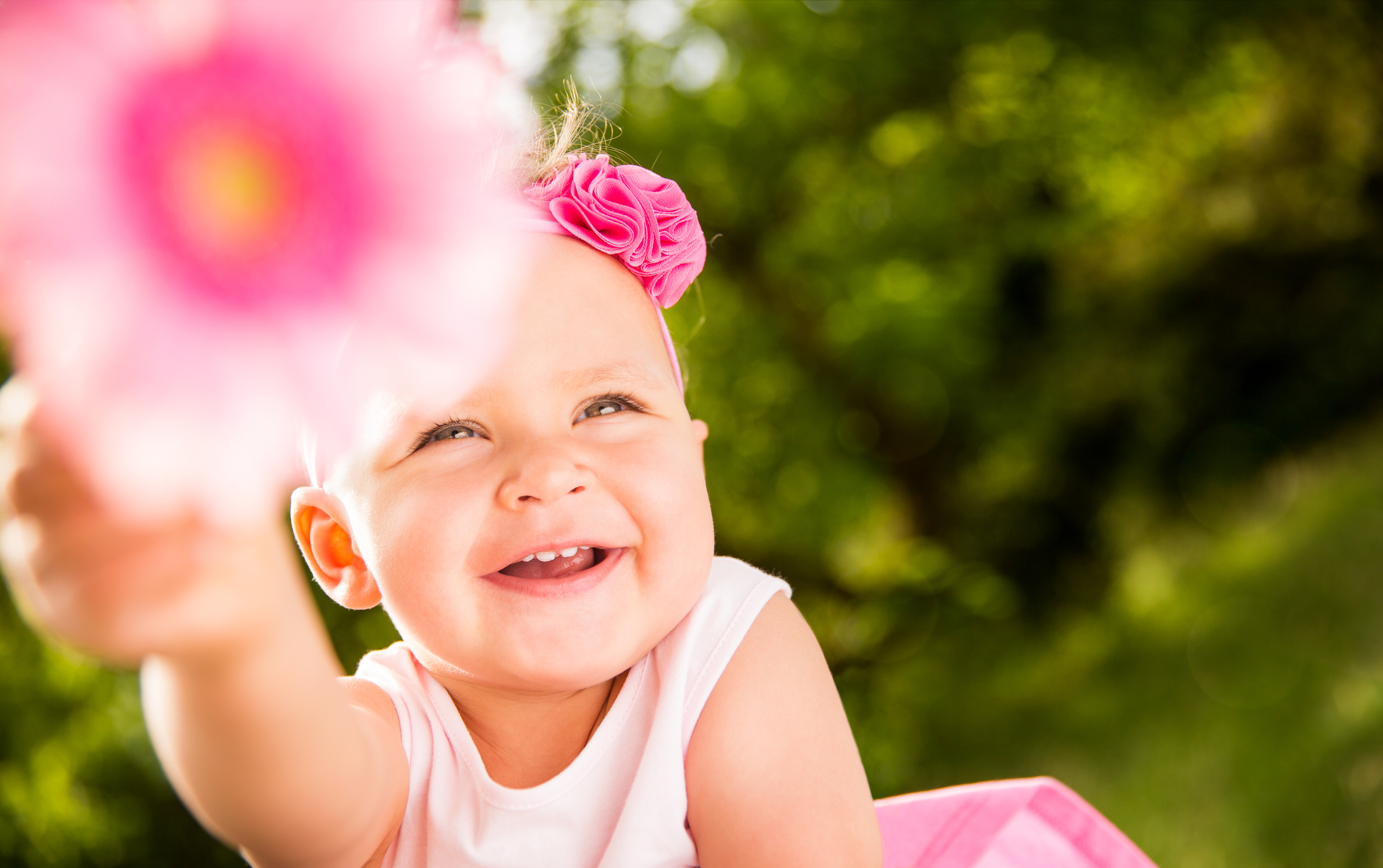 Smiling Baby girl pointing flower at camera