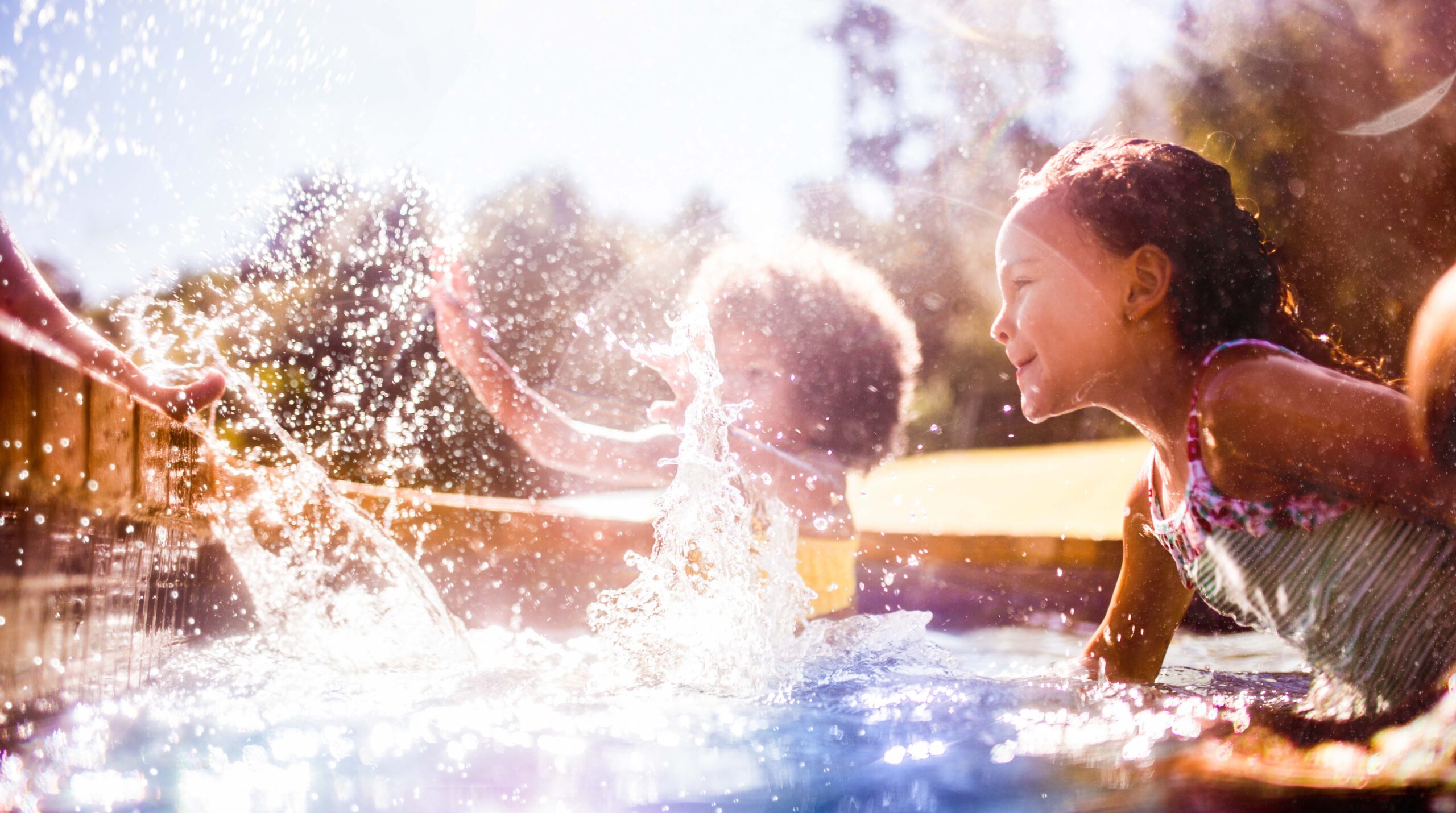 Little Afro girl and friends splashing in a pool together