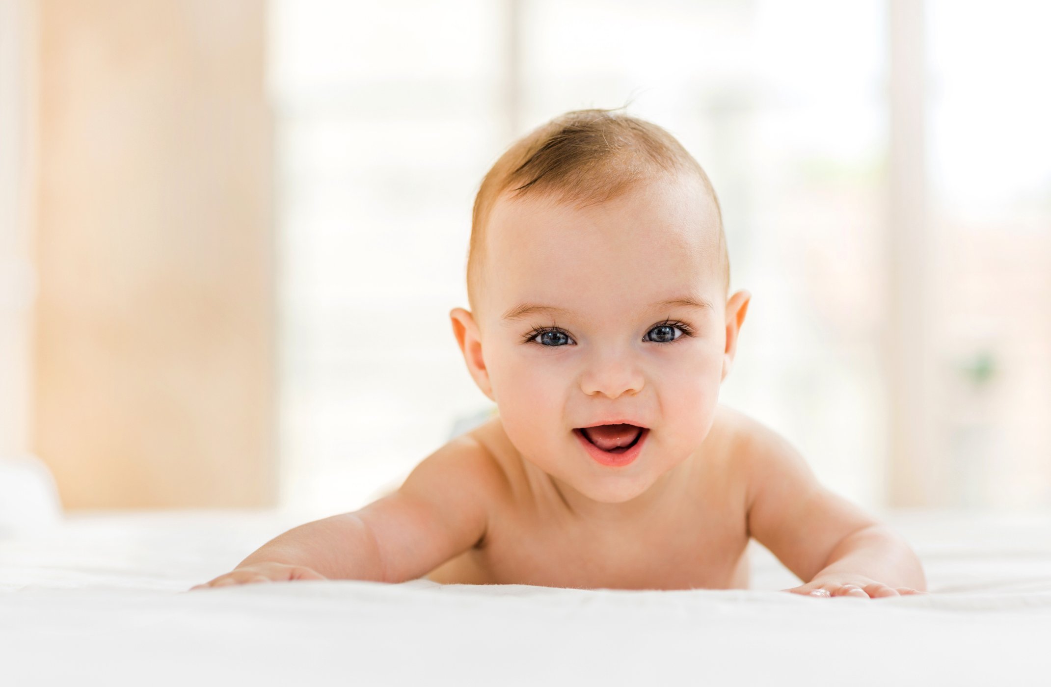 Cute baby in bed smiling and looking at camera.