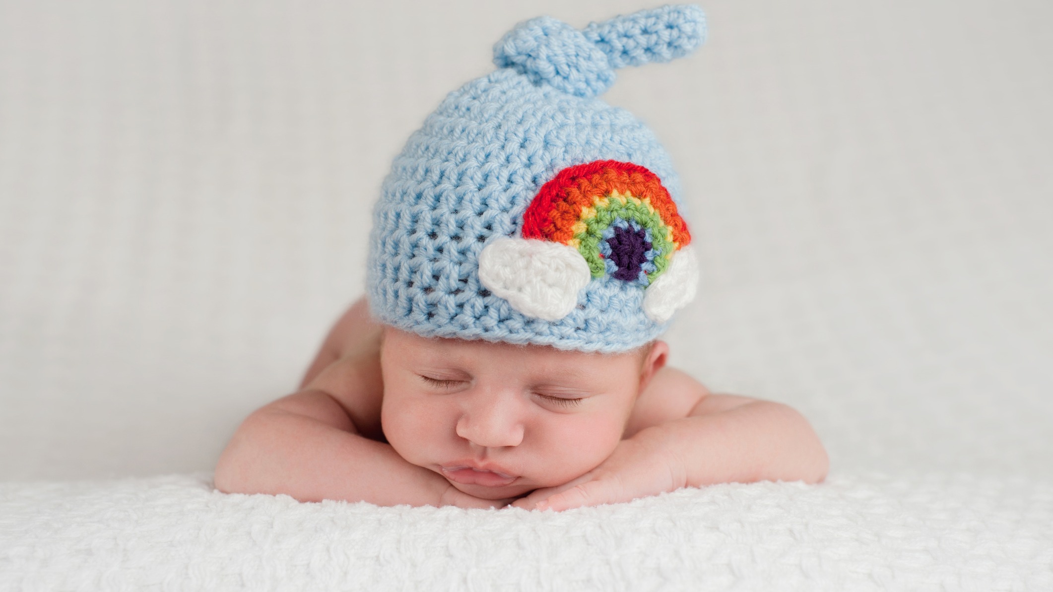 A baby with a rainbow hat on