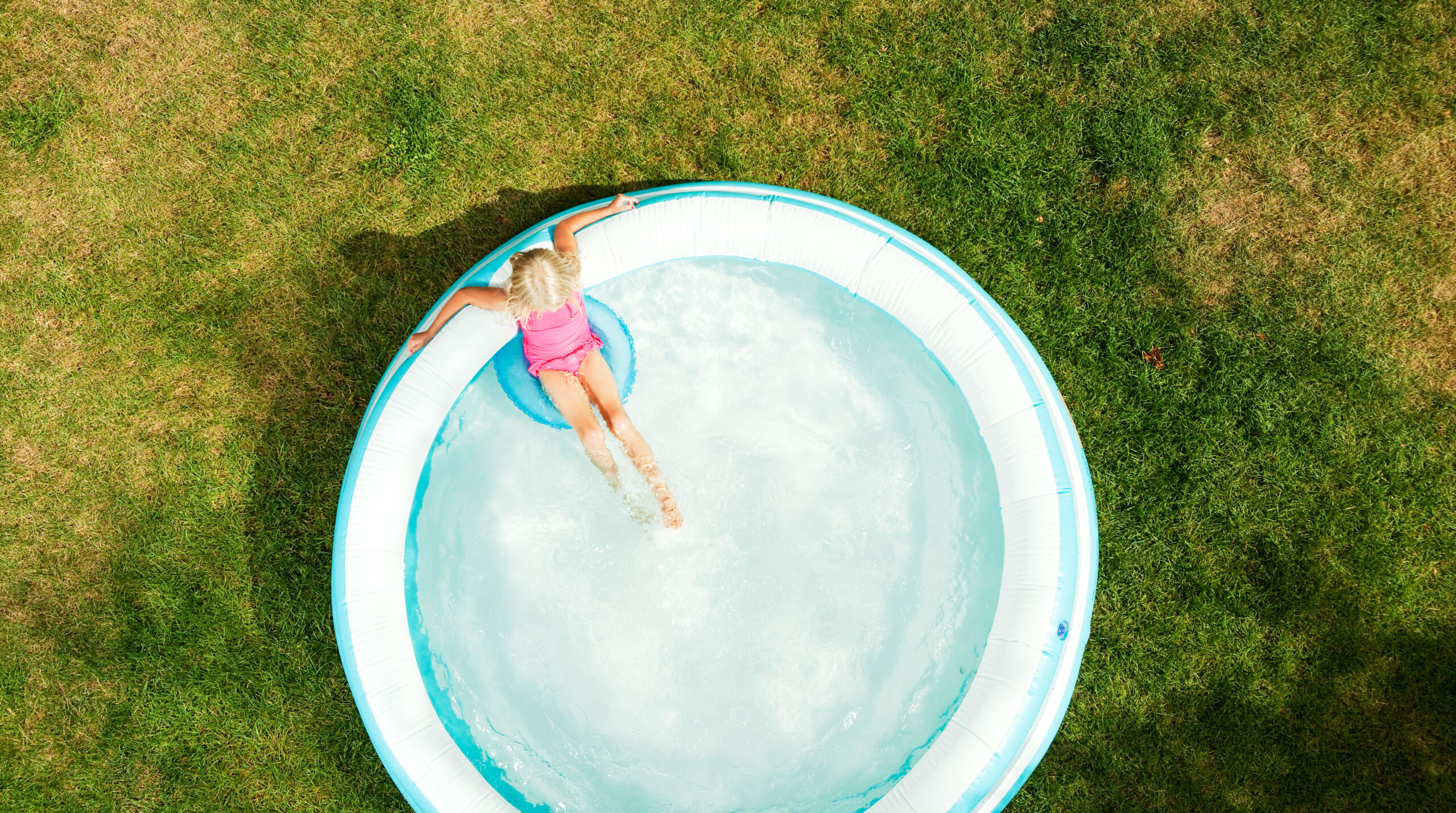 Girl in Inflatable Swimming Pool, Summer Day on Dried Grass