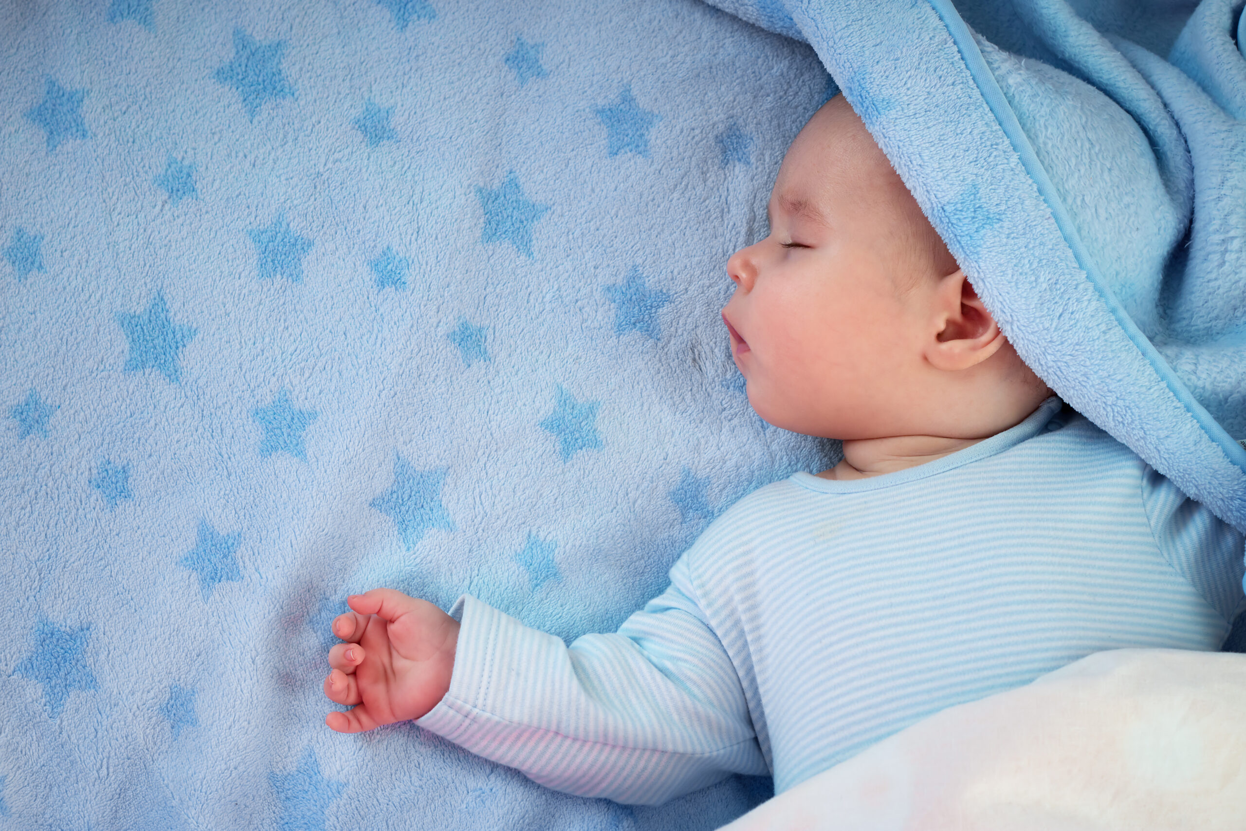three month old baby sleeping on blue blanket