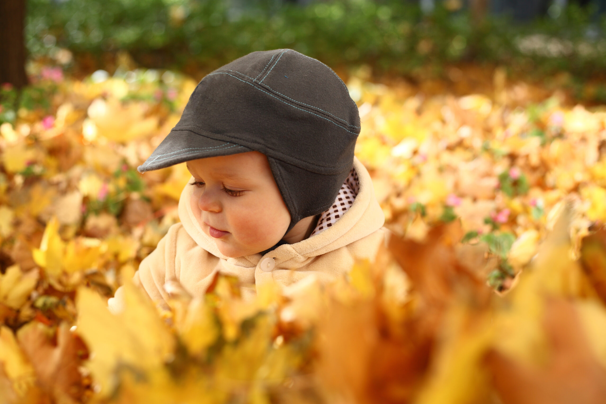 Baby boy in a pile of autumn yellow leaves