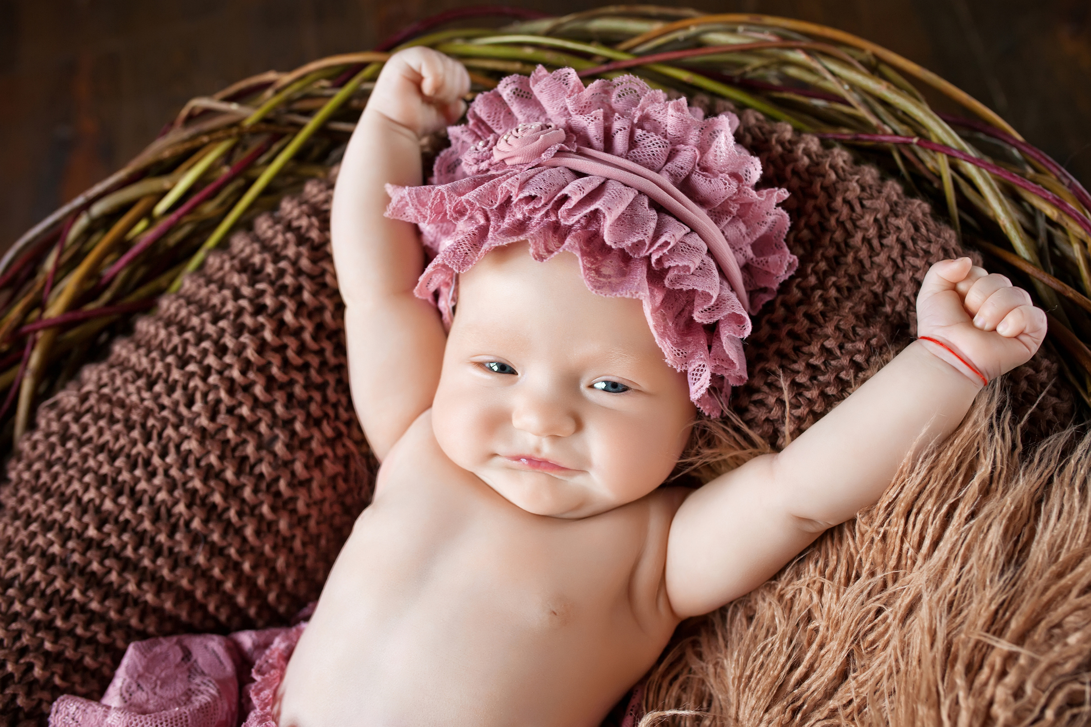 Lovely little baby girl lies in a basket and stretches