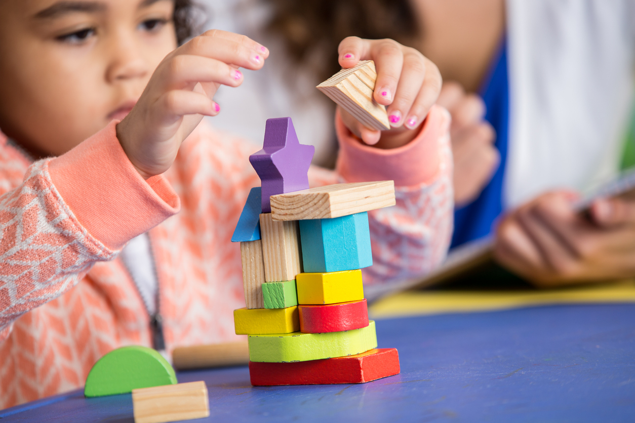 Focused little girl builds something in preschool