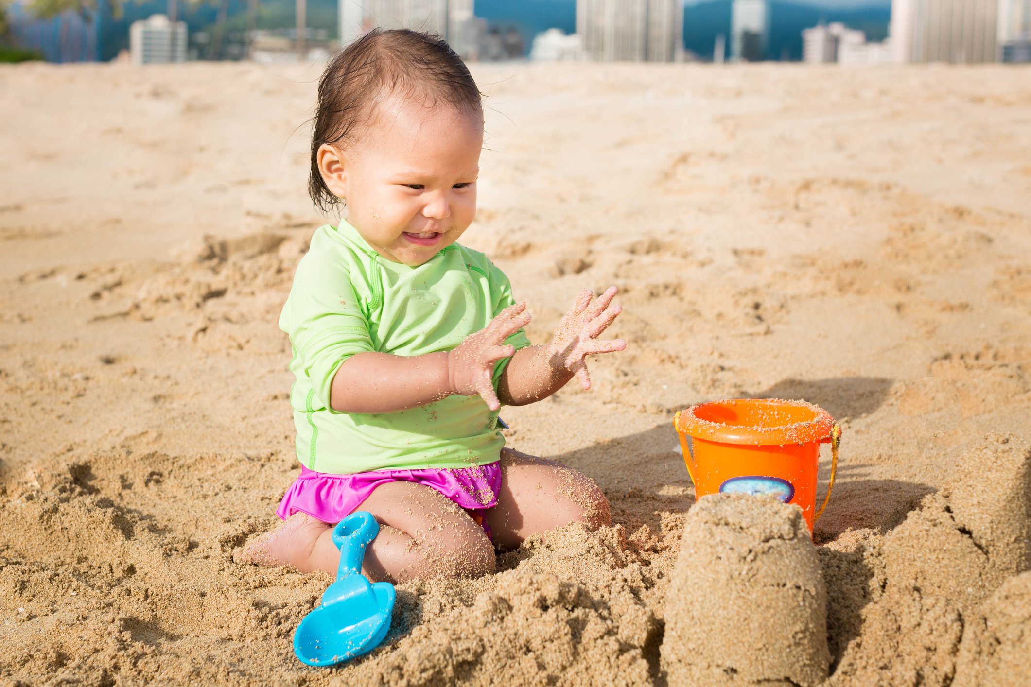 Cutest toddler playing with sand castles at the beach on a sunny summer day.