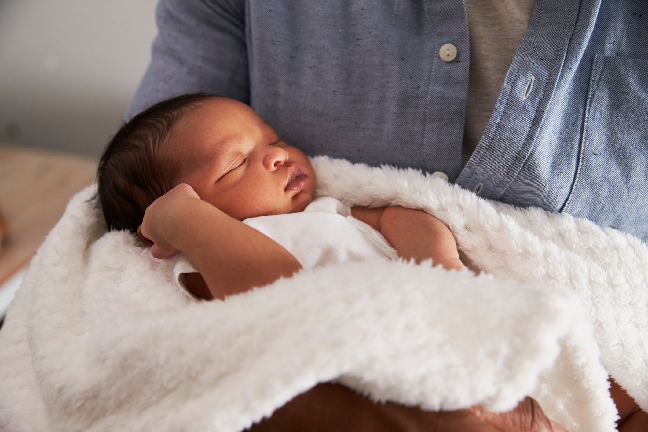 Close Up Of Father Holding Newborn Baby Son In Nursery