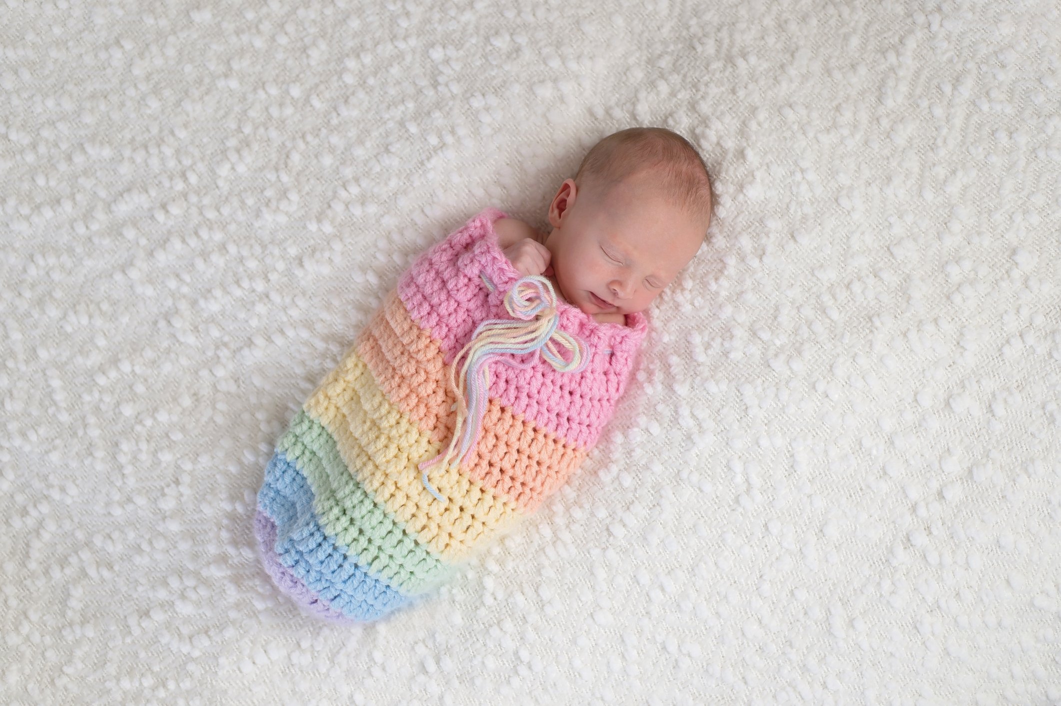 Newborn Baby Girl in a Rainbow Colored Pouch