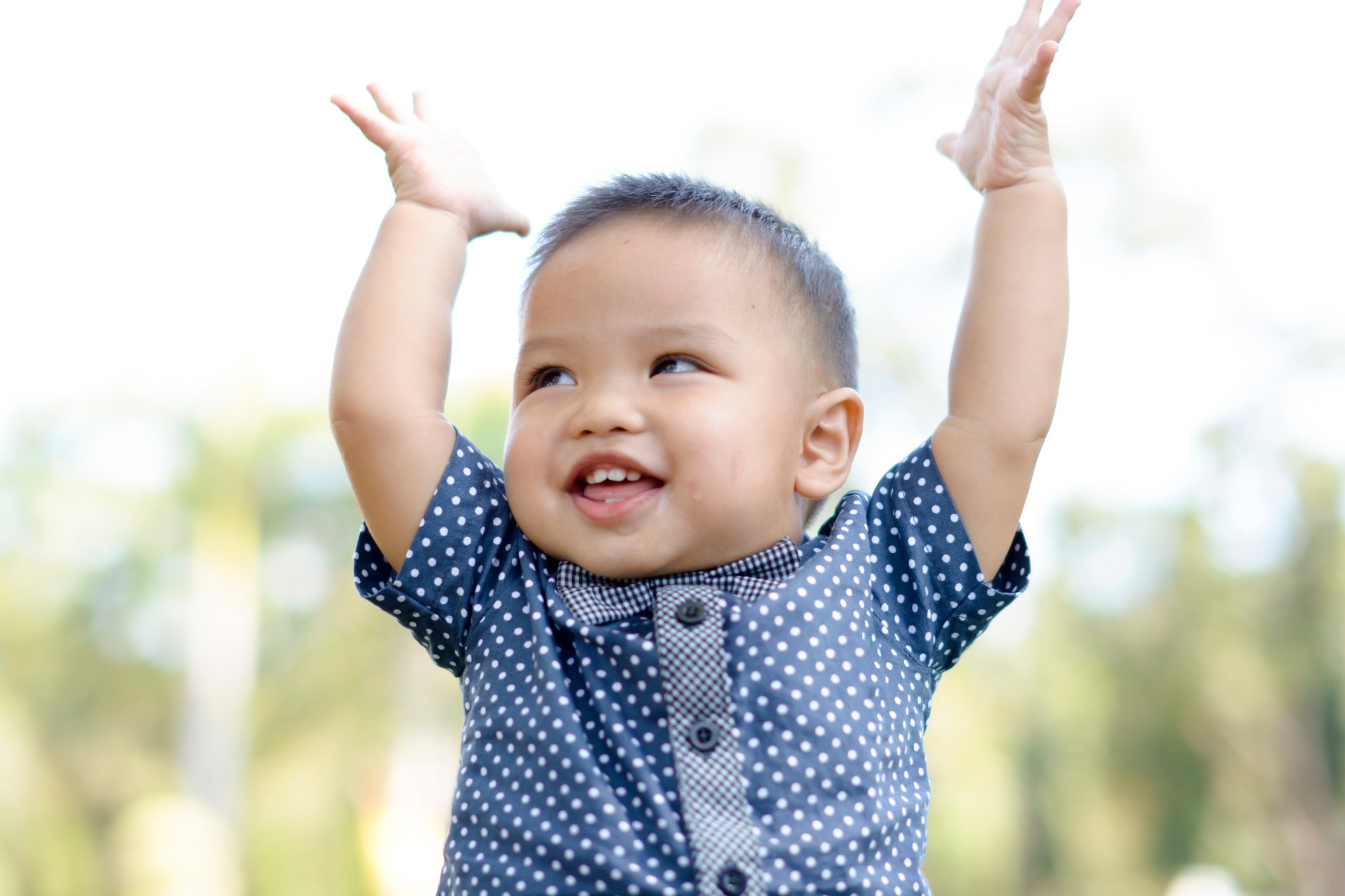 Cute asian boy raise hands and smile.