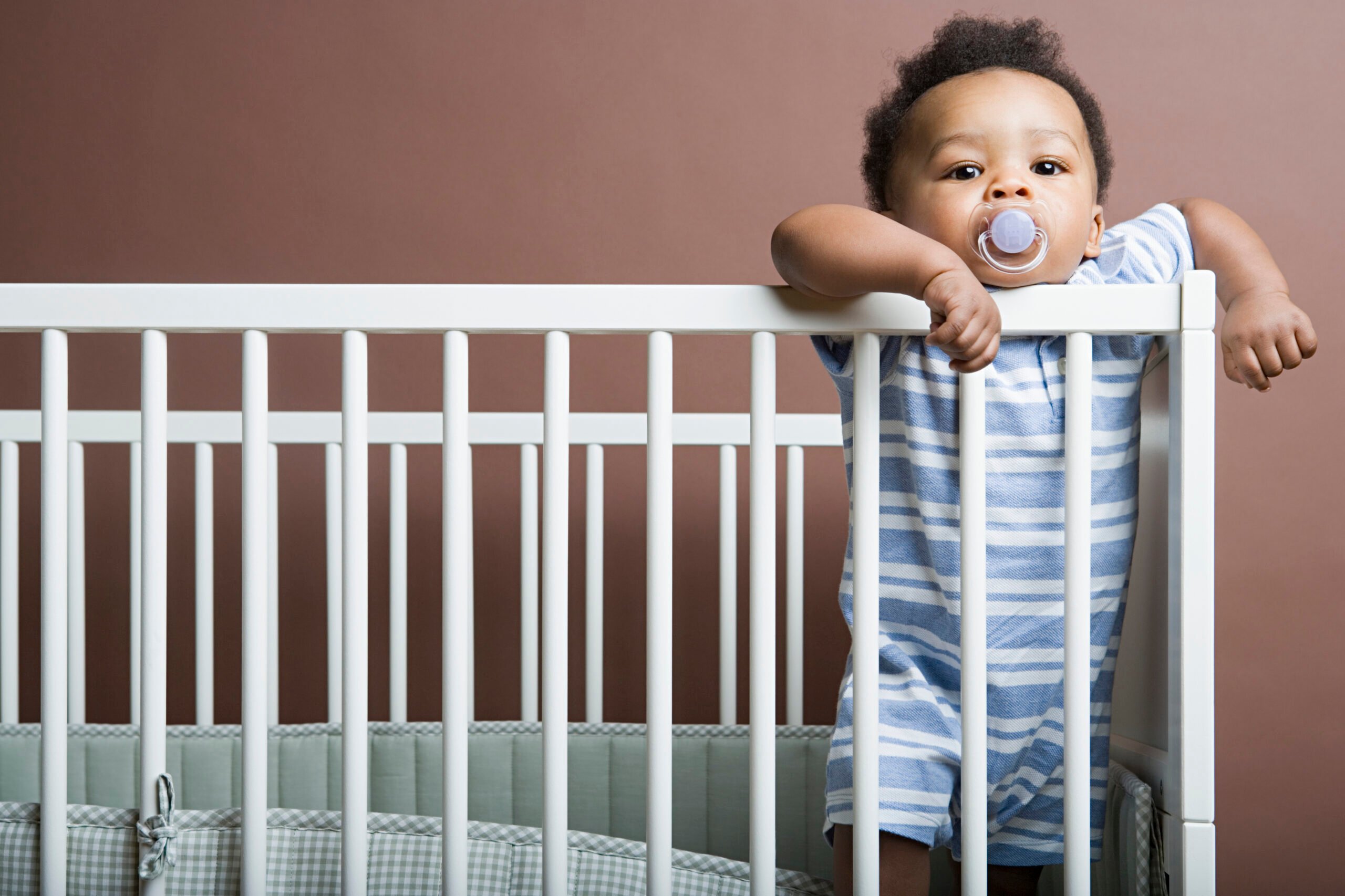 Baby boy standing in cot