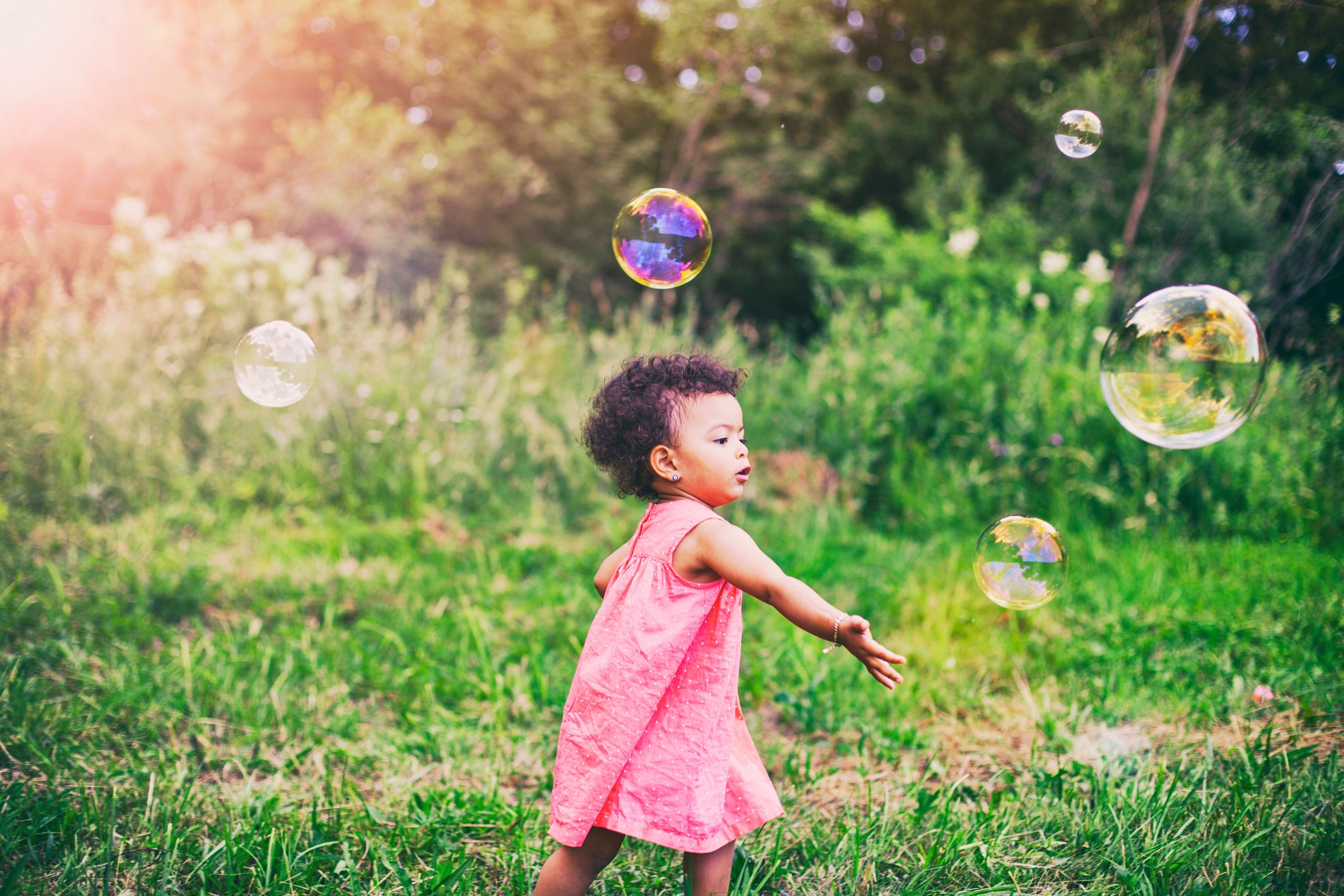 African-American baby girl playing with soap bubbles in the park