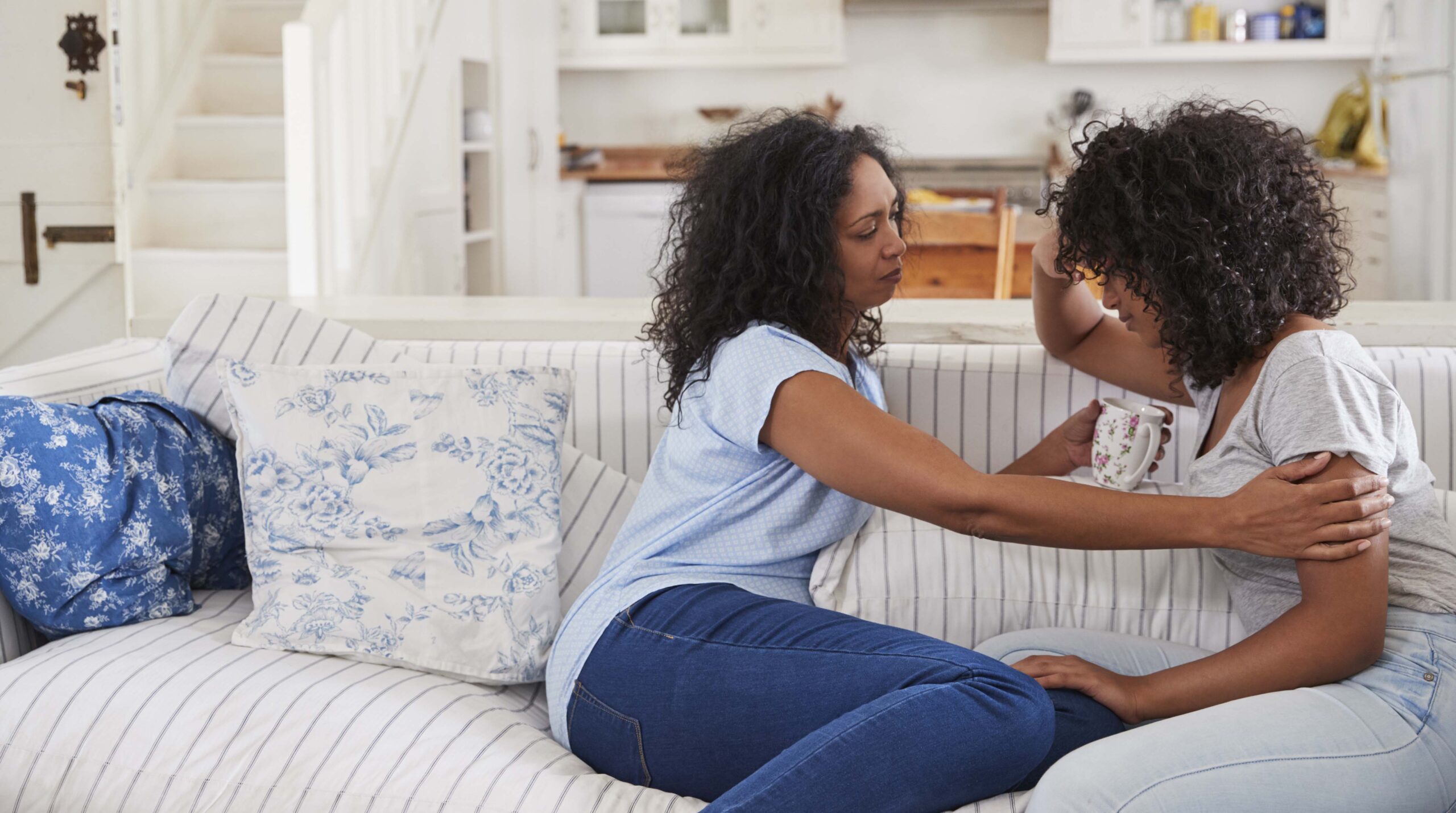 Mother Talking With Unhappy Teenage Daughter On Sofa