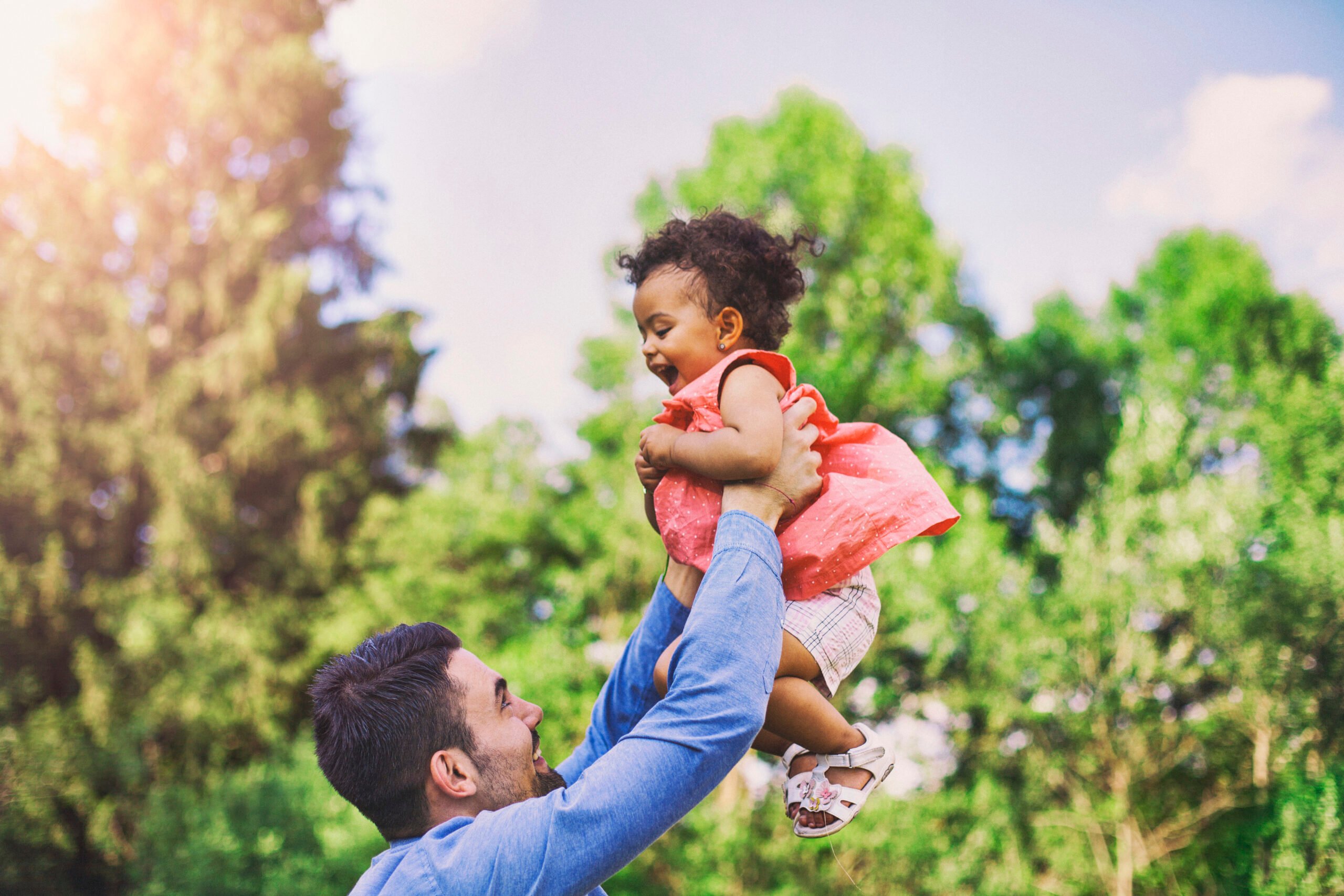 Father throwing his baby daughter in the air in a park