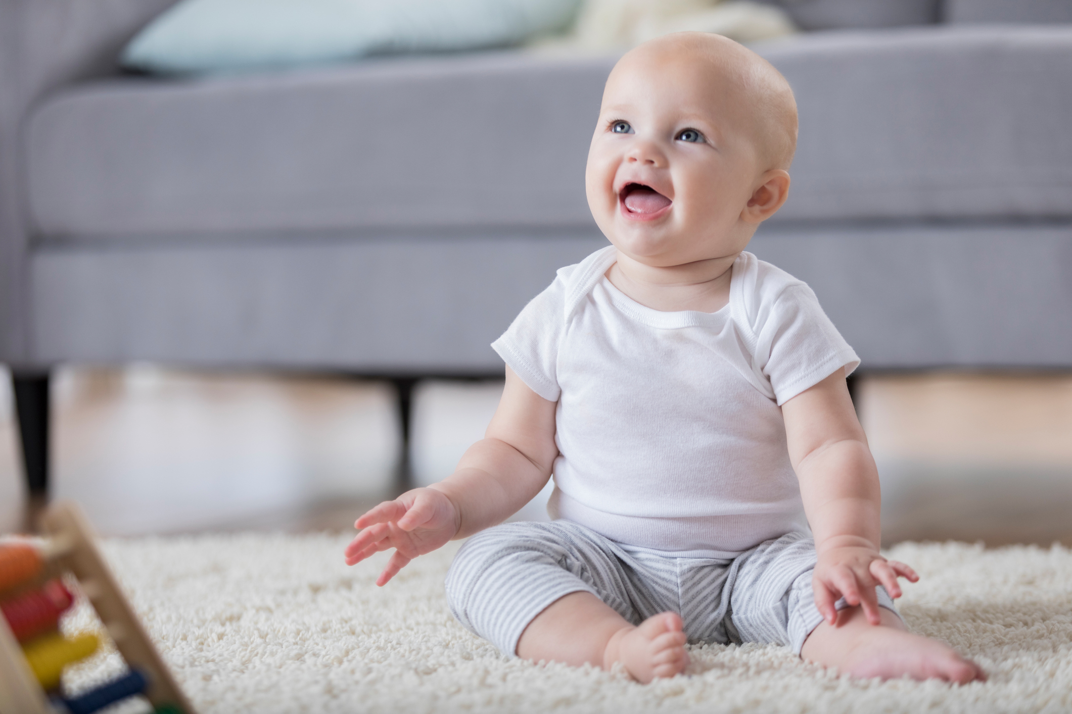 Adorable smiling baby sitting on floor and looking up