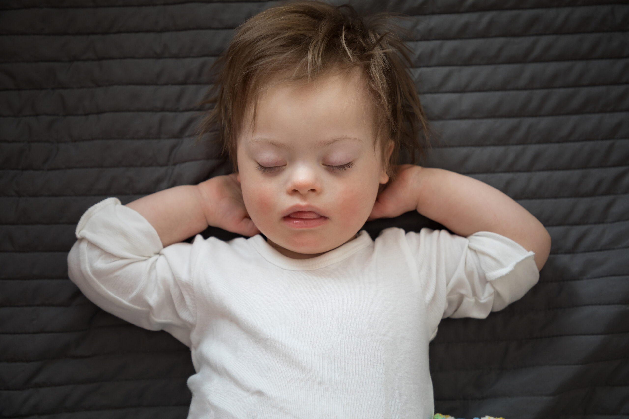 Cute baby boy with Down syndrome sleeping on the bed