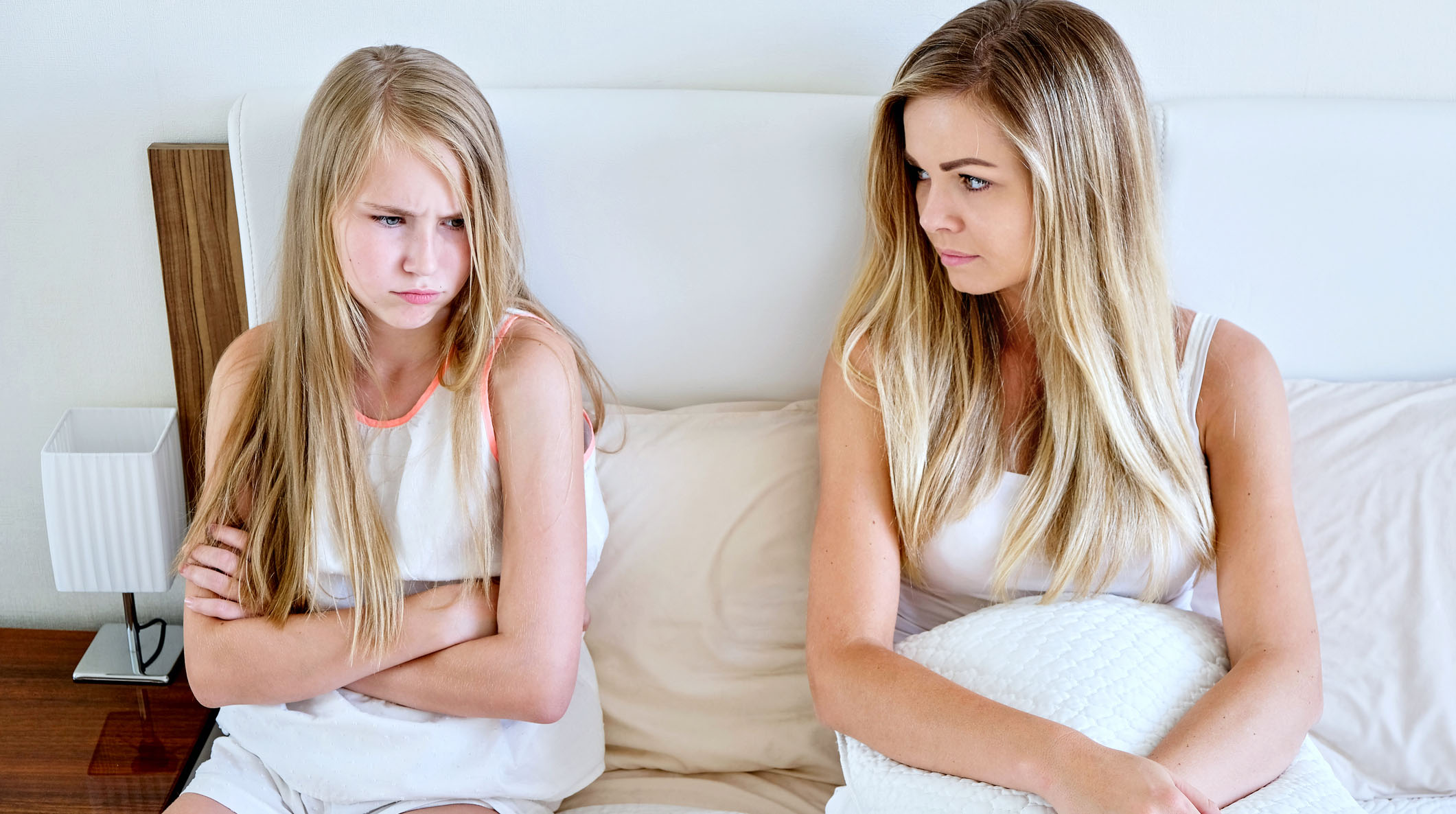 Mother and daughter sitting on a mattress looking sad