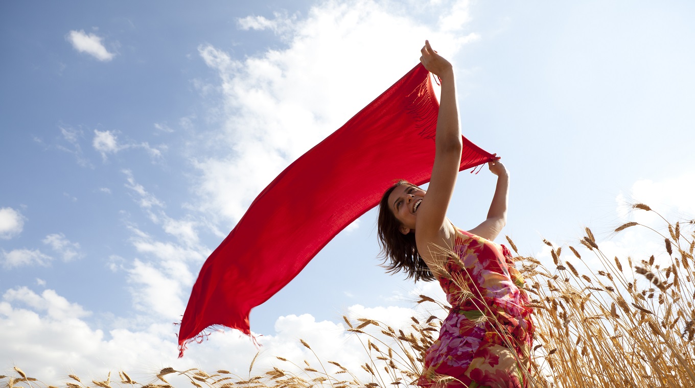 Young Woman Wearing Red Dress Holding Reddish Scarf In Wind