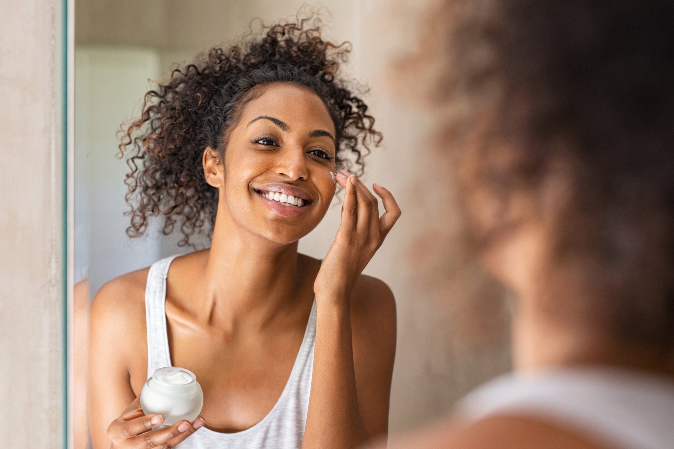 woman moisturizing face in mirror