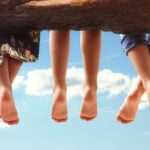 Children sitting in a tree dangling their feet