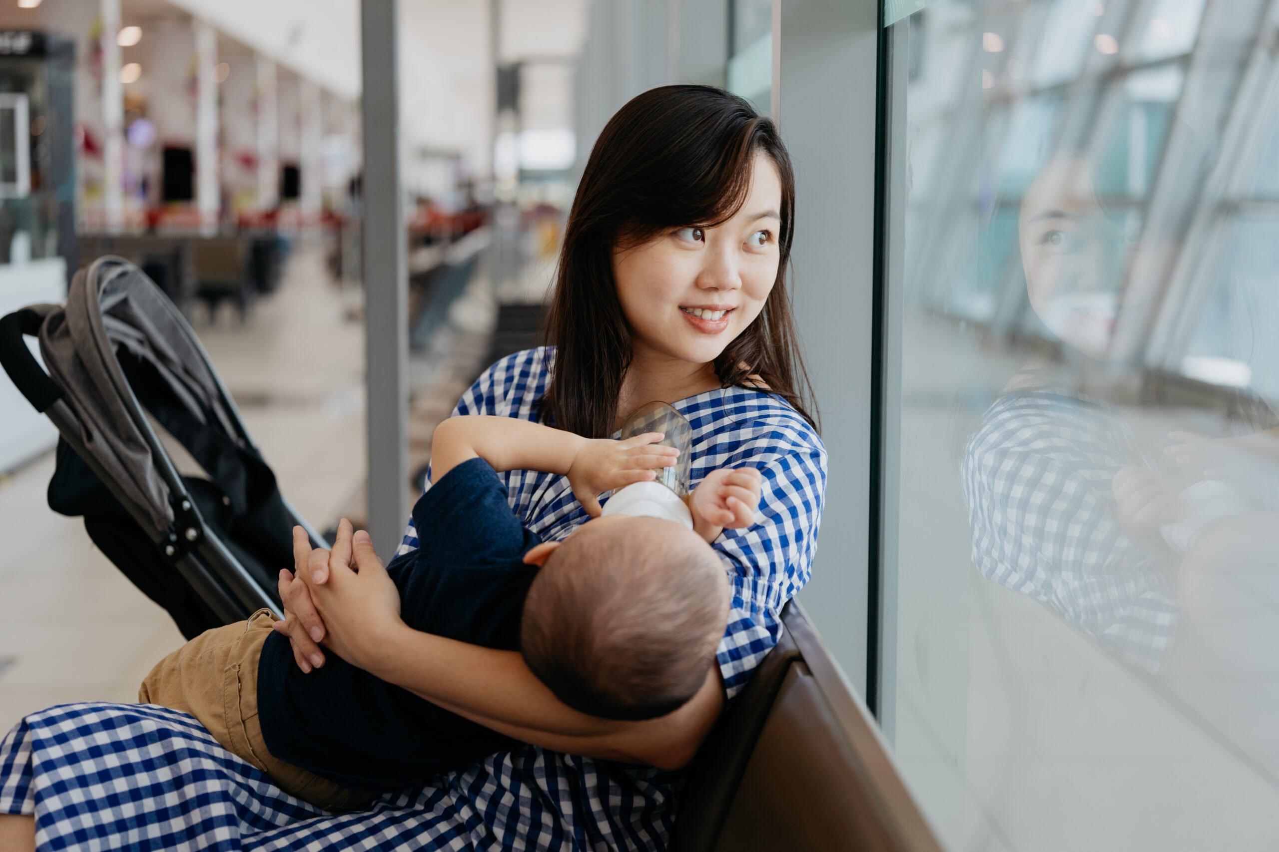 An Asian Chinese woman feeding her baby while waiting for flight at the airport