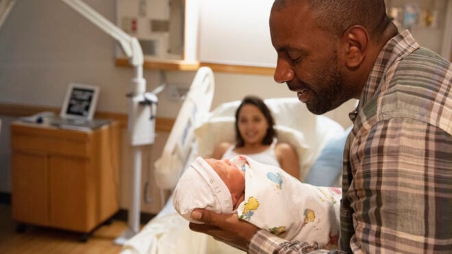 Father holding newborn baby at hospital
