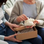 Woman giving gift box with knit baby booties