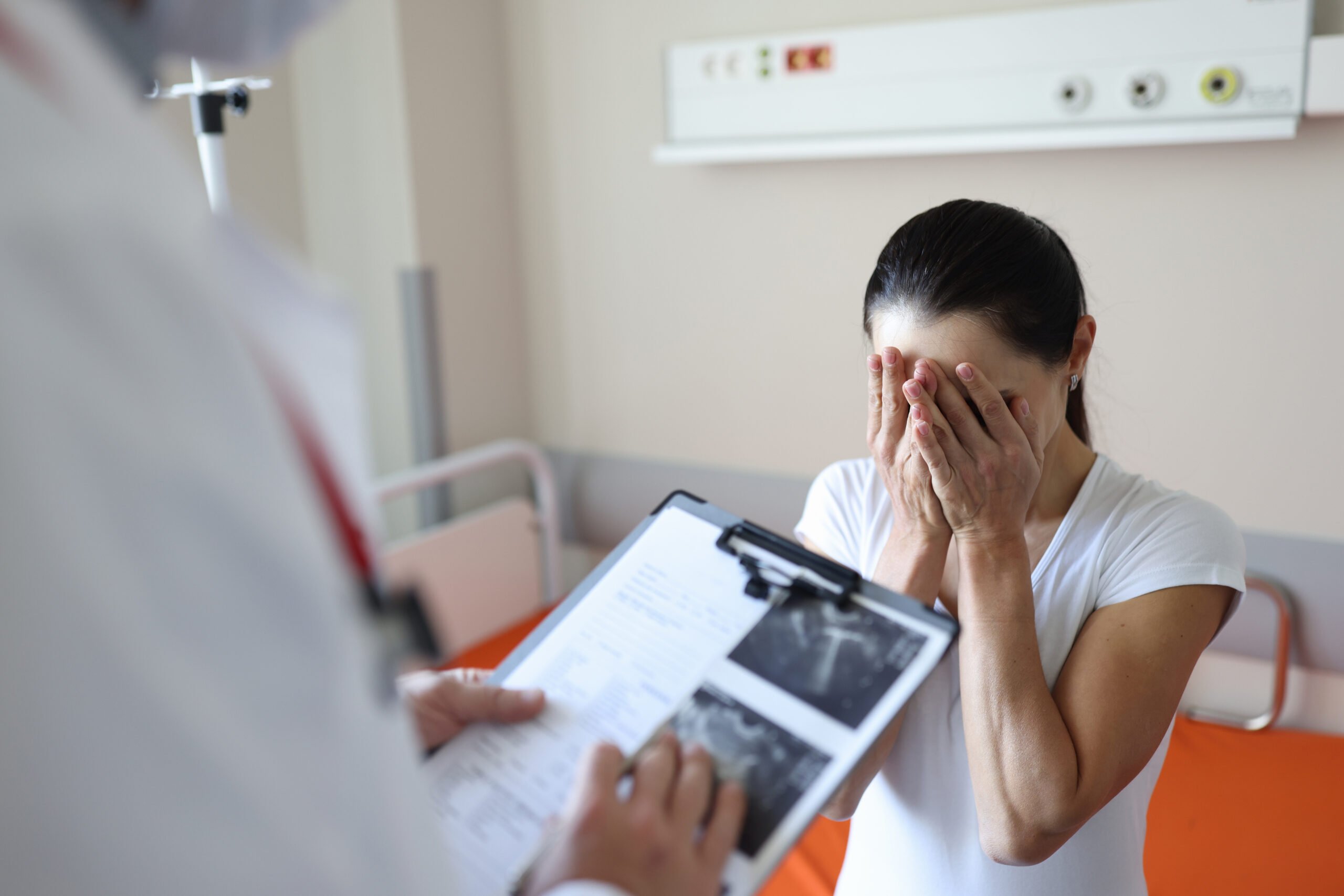 Doctor holding documents in front of crying patient in clinic. Psychological support for people with cancer concept