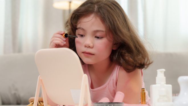 young child doing makeup in front of a small mirror