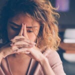 Tired Young Woman Leaning Head on Hands