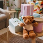 Teddy bear with gifts arranged on coffee table for baby shower party with no people