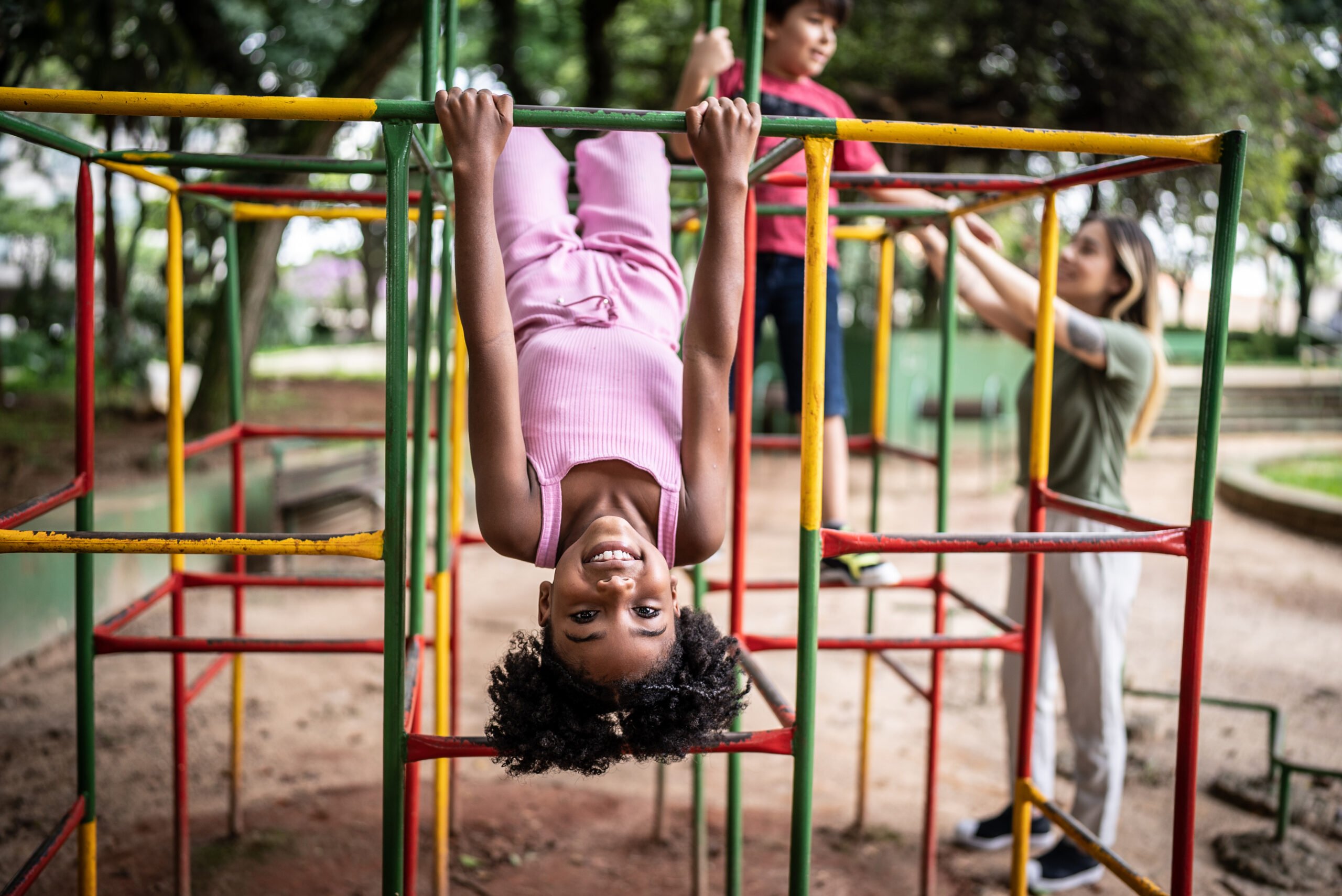 Portrait of a girl upside down in a jungle gym in a park kid playing at school