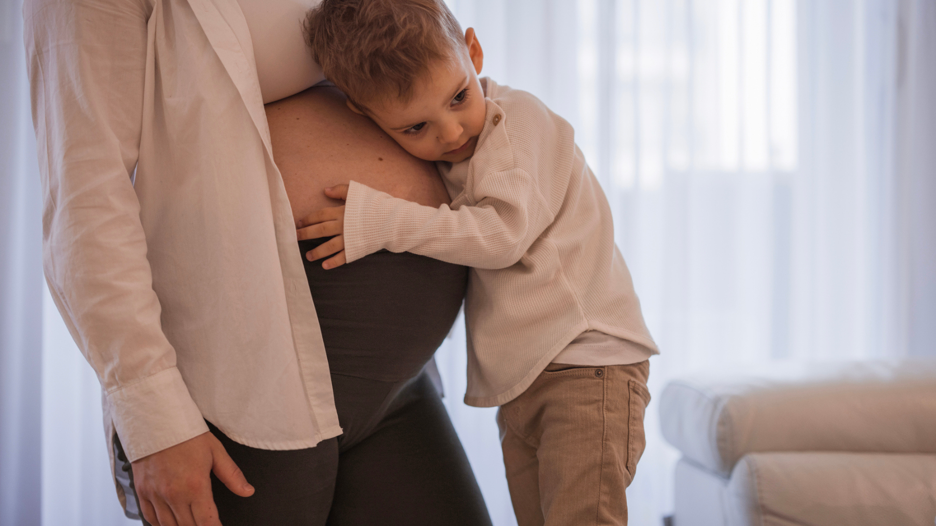 pregnant woman with toddler hugging baby bump