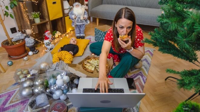Mom amid holiday chaos working on her laptop on the floor.