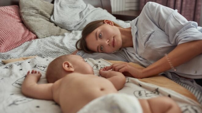 Mom and baby laying in bed, co-sleeping.