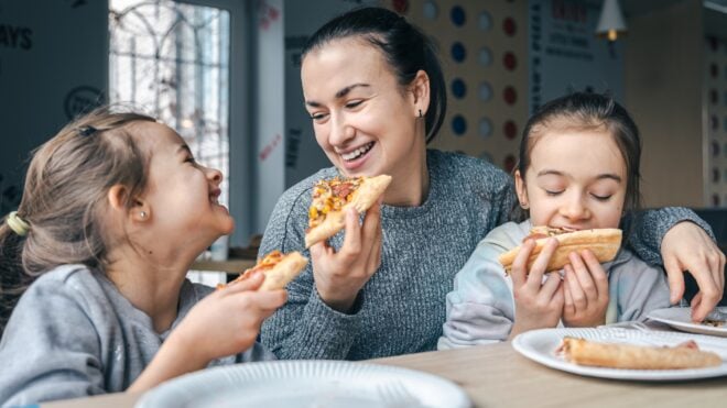 Mom and daughters eating takeout at the kitchen table