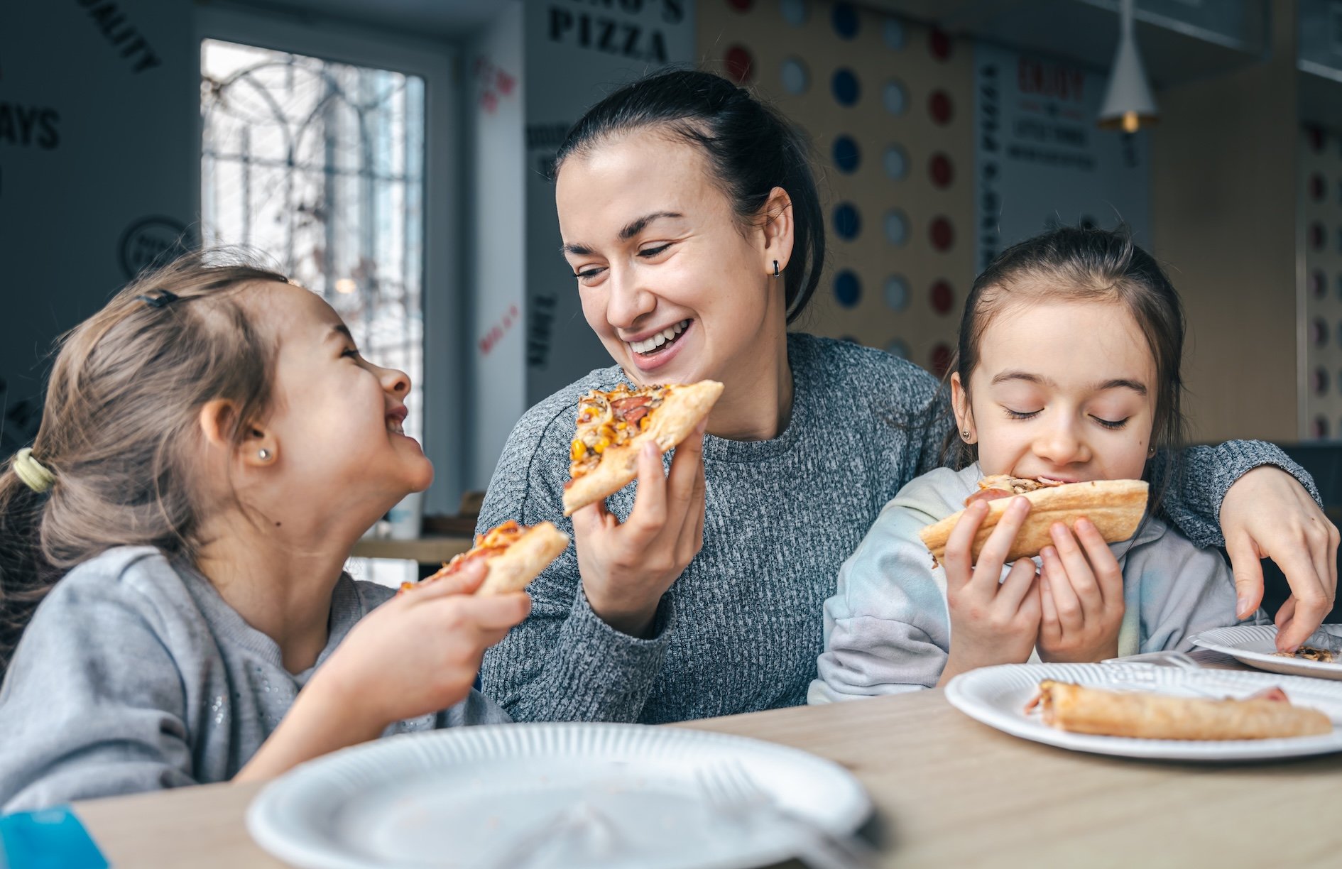 Mom and daughters eating takeout at the kitchen table