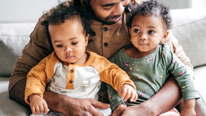 Black father holding his twin children