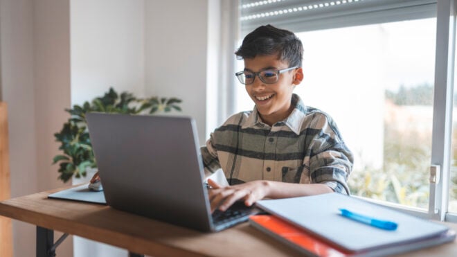 Boy using laptop studying online at home